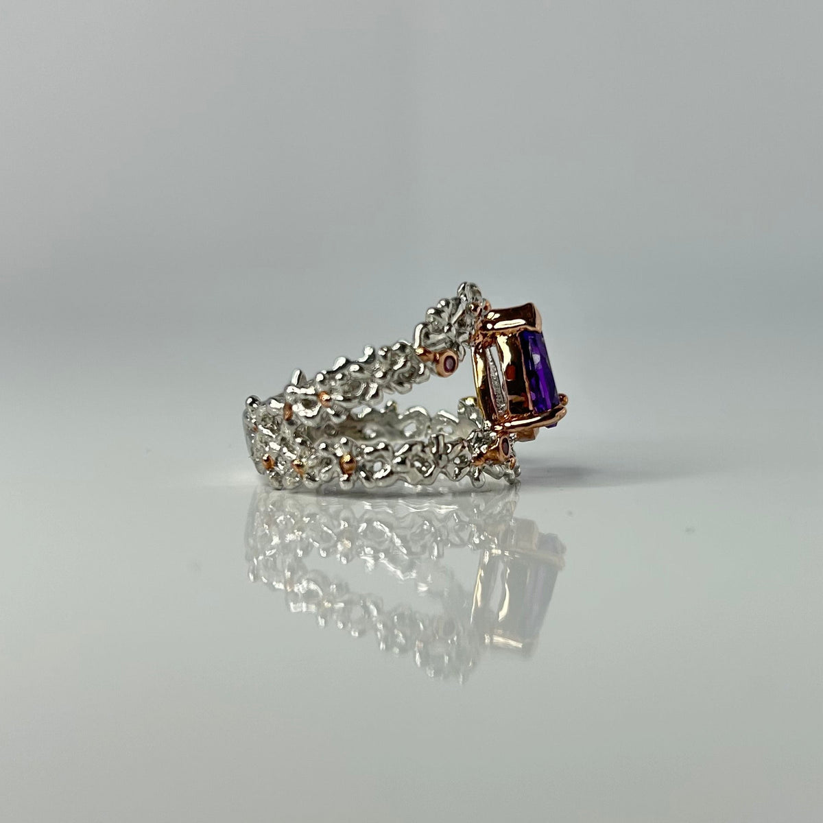 Silver ring with a purple teardrop amethyst gemstone on a light gray background