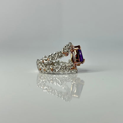 Silver ring with a purple teardrop amethyst gemstone on a light gray background