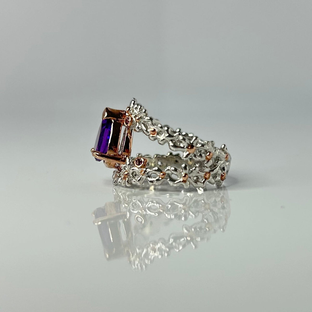 Silver ring with a purple teardrop amethyst gemstone on a light gray background