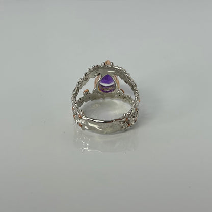 Silver ring with a purple teardrop amethyst gemstone on a light gray background