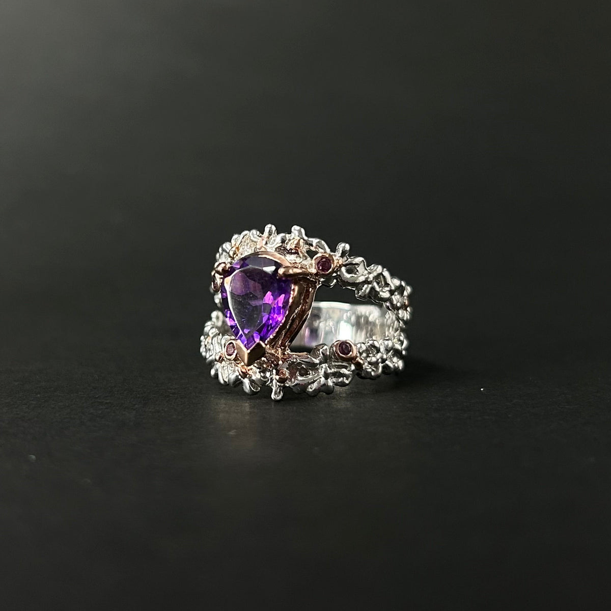 Silver ring with a purple amethyst gemstone on a black background