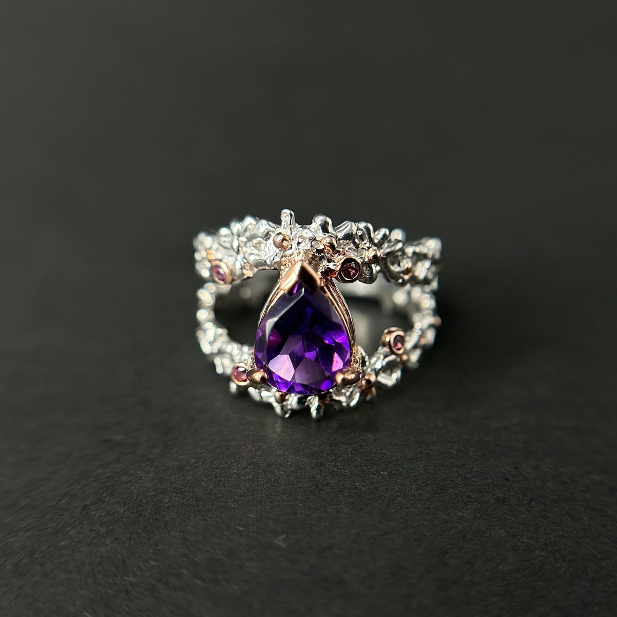 Silver ring with a purple amethyst gemstone on a black background