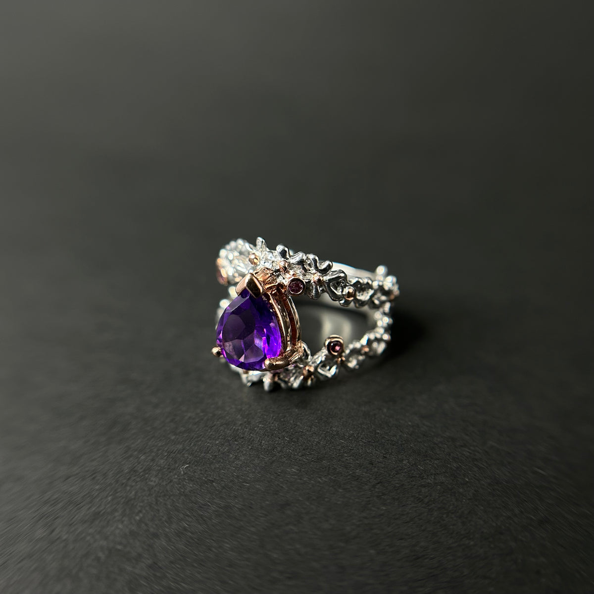 Silver ring with a purple amethyst gemstone on a black background