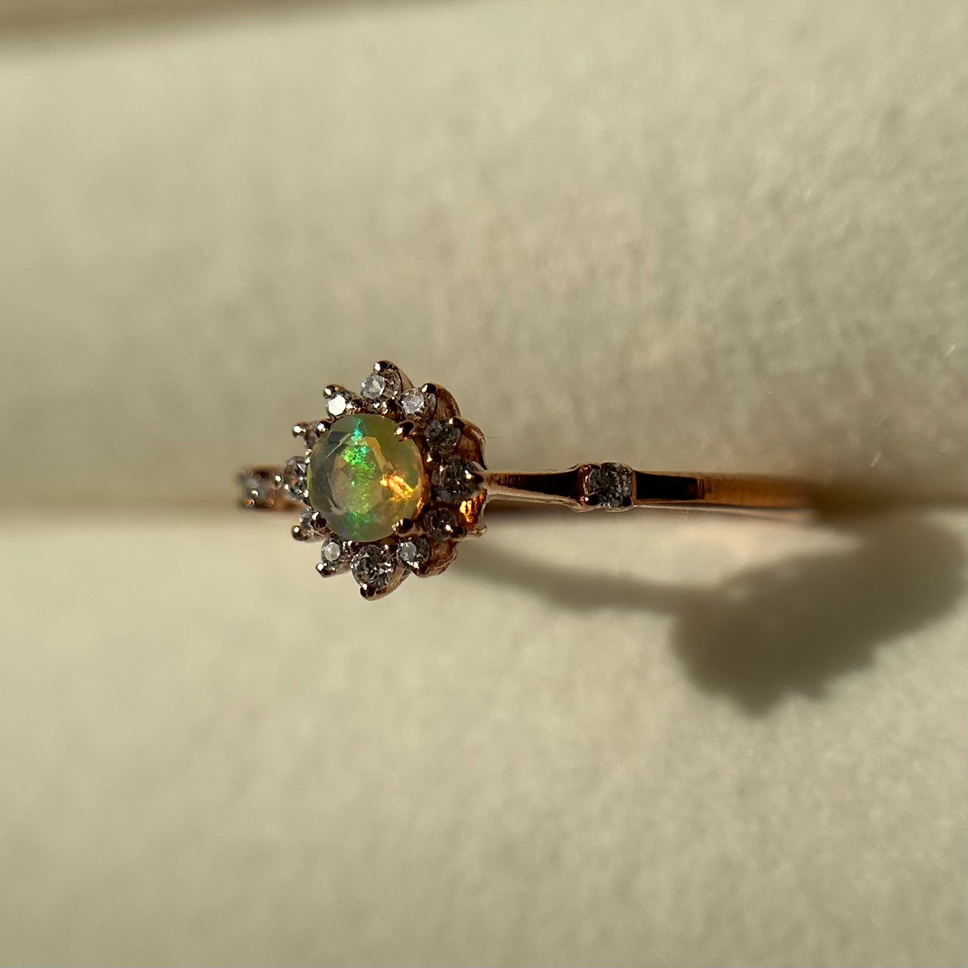 Silver ring with an opal stone and diamond accents on a neutral background