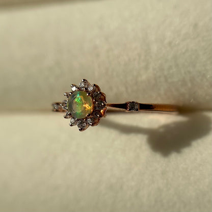 Silver ring with an opal stone and diamond accents on a neutral background