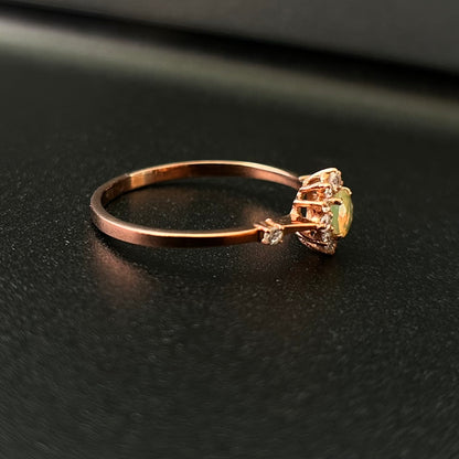 Silver ring with an opal stone on a black surface.