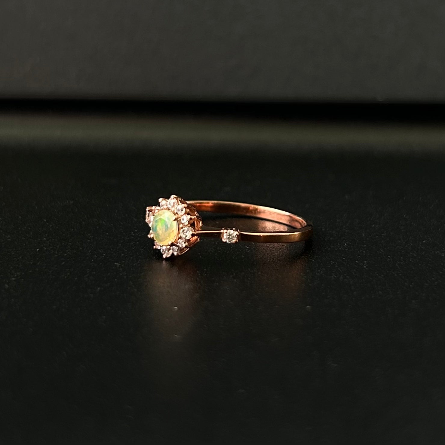 Silver ring with an opal stone on a black surface.