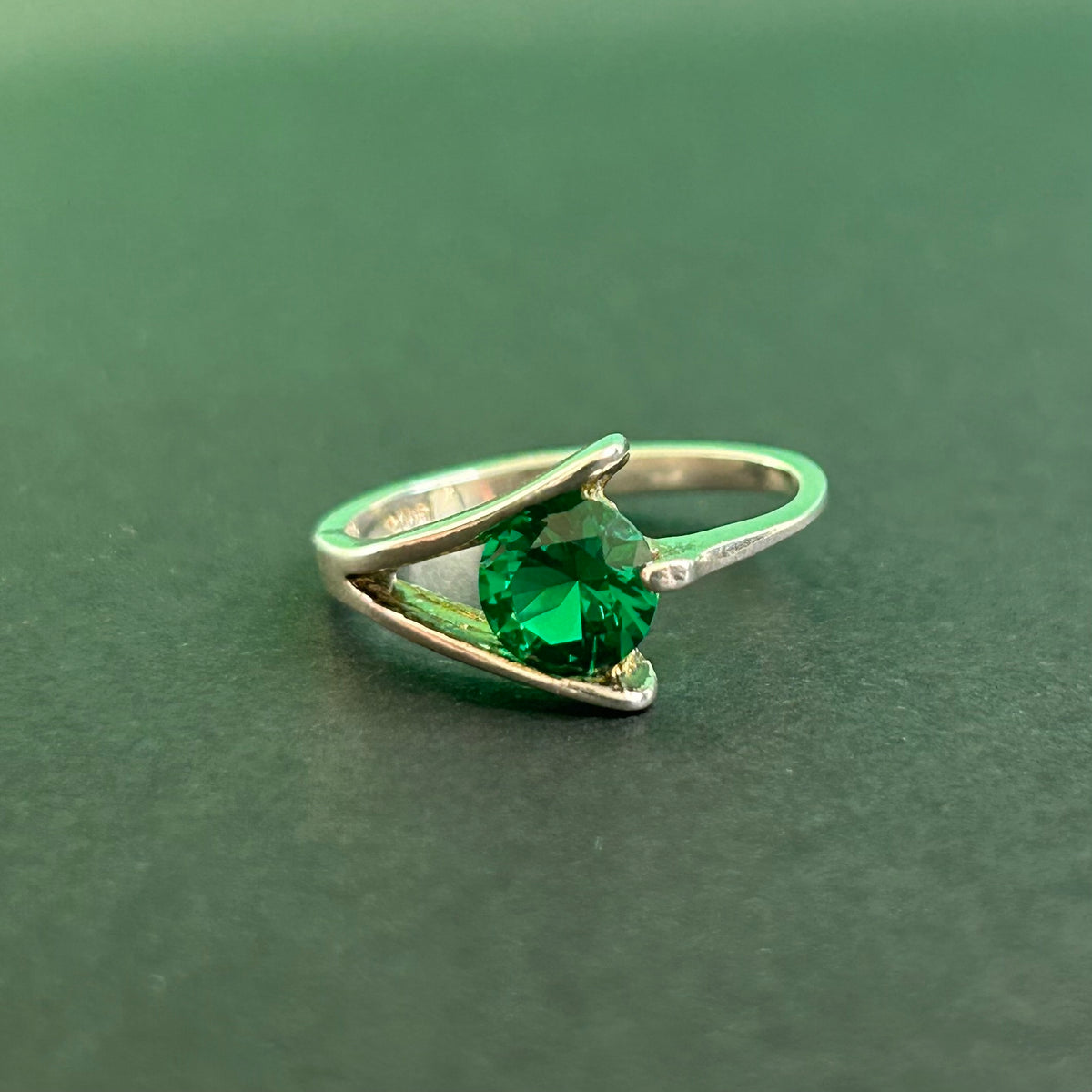 Silver ring with a green gemstone on a green background