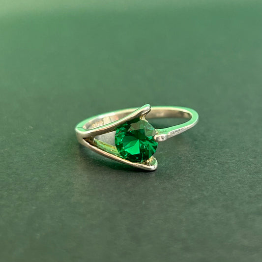 Silver ring with a green gemstone on a green background