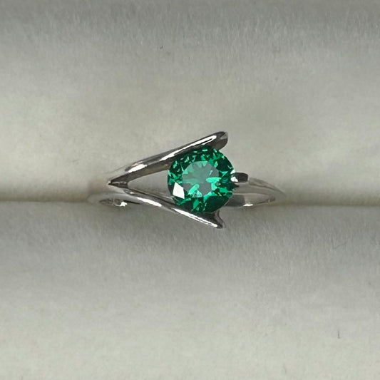 Silver ring with a green gemstone on a light gray background