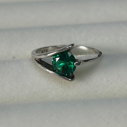 Silver ring with a green gemstone on a light gray background