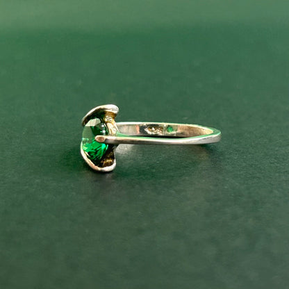 Silver ring with a green gemstone on a dark green background