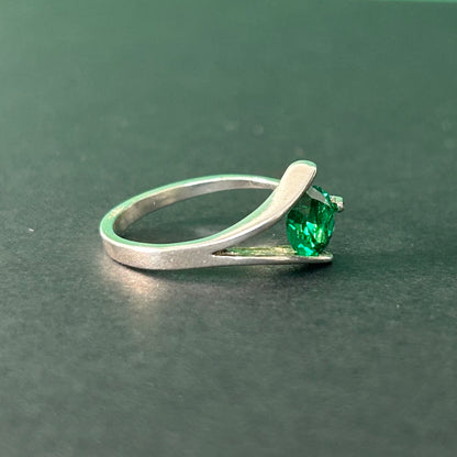 Silver ring with a green gemstone on a dark green background
