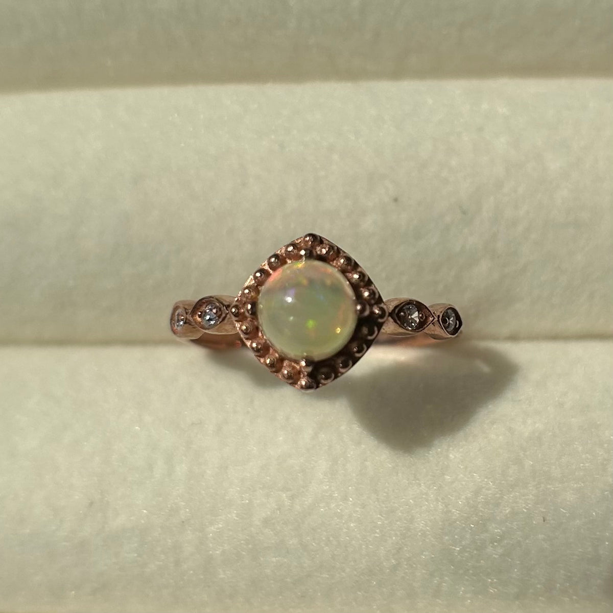 Silver ring with a central opal on a light background