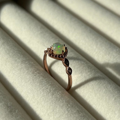 Silver ring with a central opal on a light background