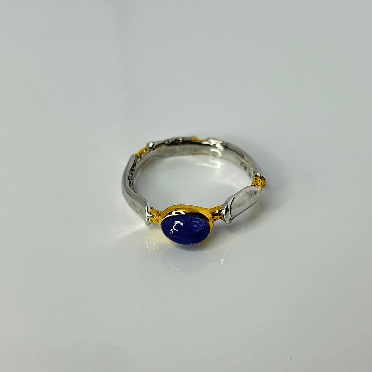 Silver ring with a blue gemstone on a light gray background