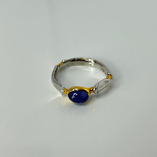 Silver ring with a blue gemstone on a light gray background