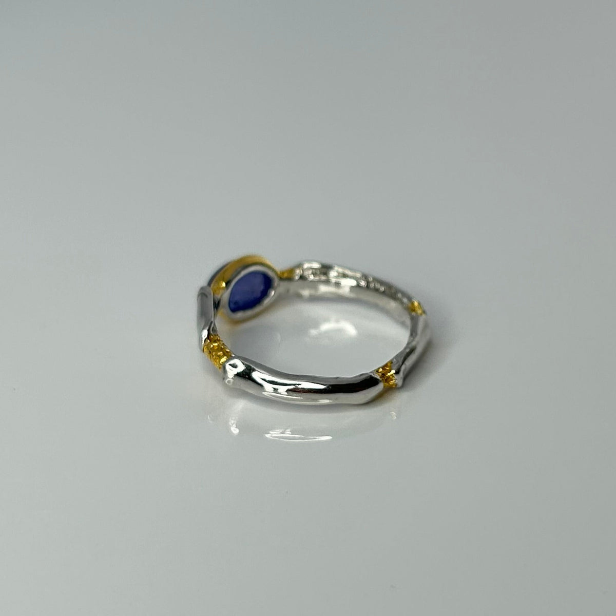 Silver ring with a blue tanzanite gemstone on a light gray background