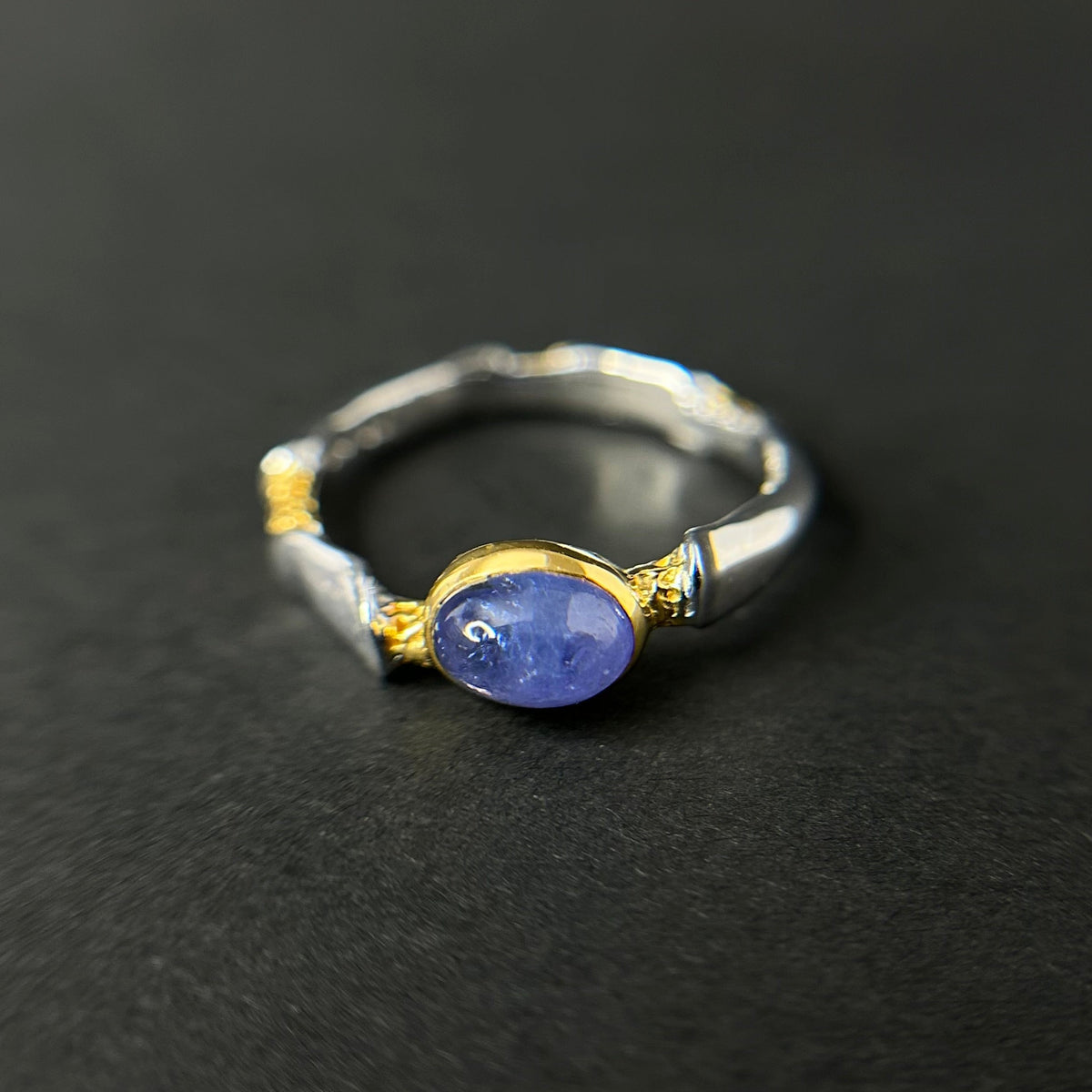 Silver and gold ring with a tanzanite gemstone on a black background