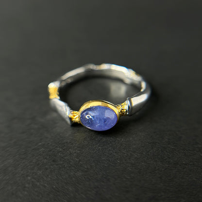 Silver and gold ring with a tanzanite gemstone on a black background