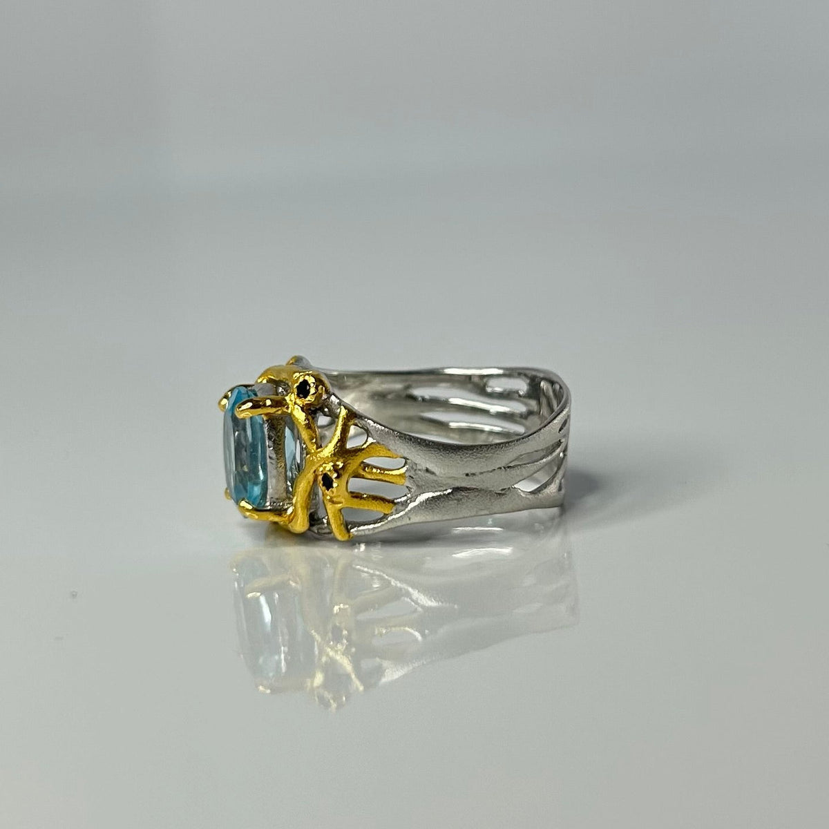 Two-tone ring with a blue gemstone on a gray background