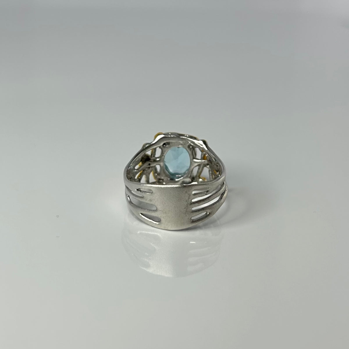 Silver ring with a light blue gemstone on a gray background