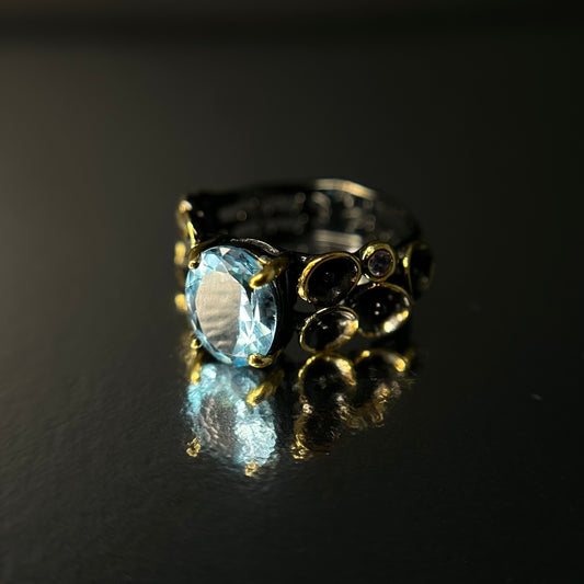 Silver ring with a blue topaz gemstone on a black background
