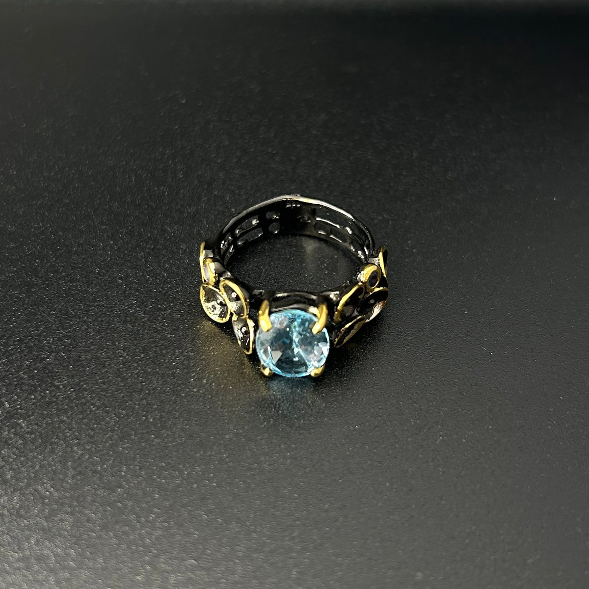 Ring with a blue gemstone and gold accents on a dark surface