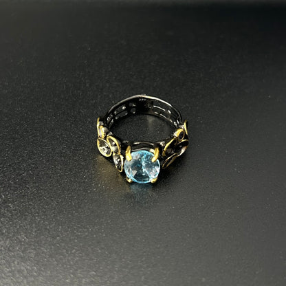 Ring with a blue gemstone and gold accents on a dark surface