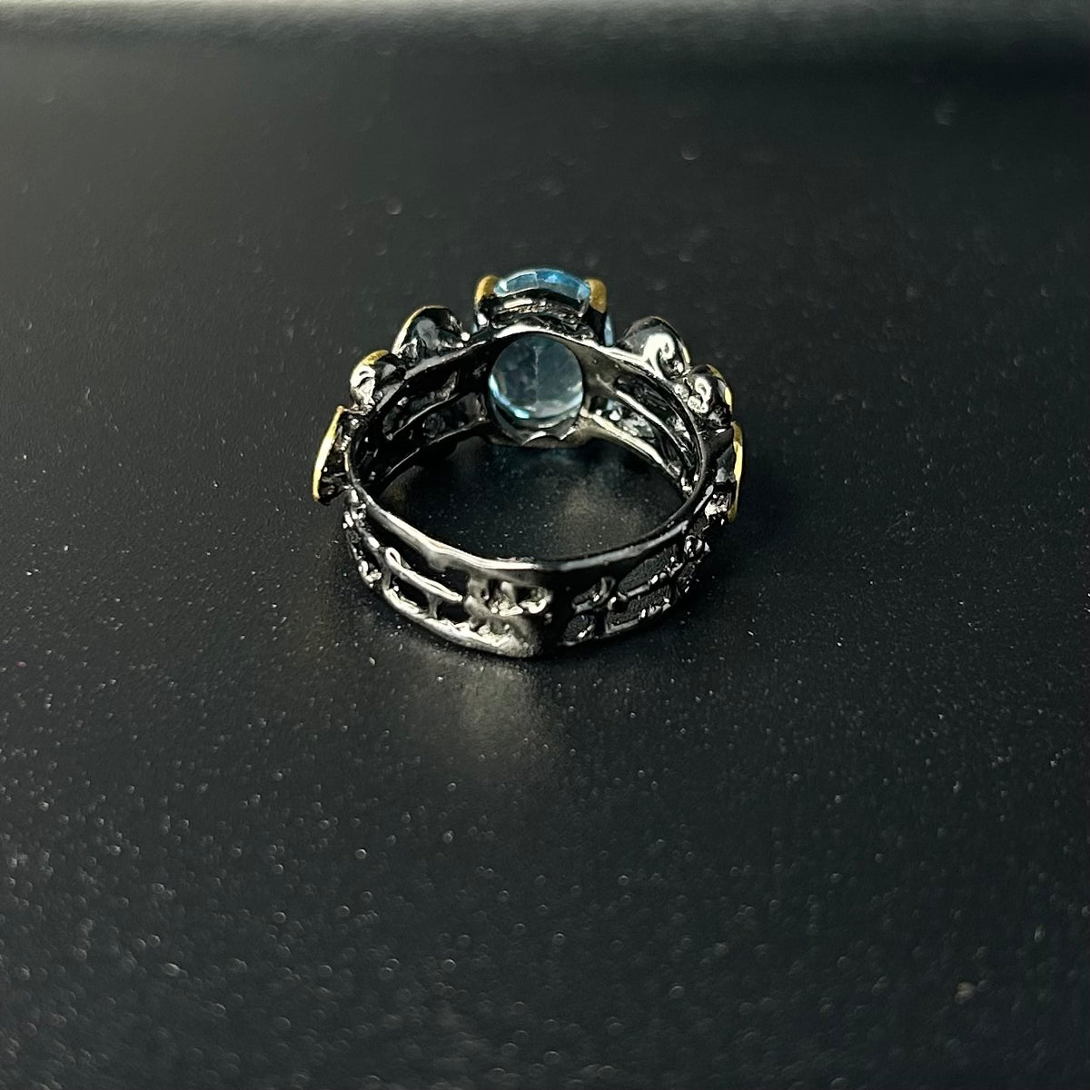 Silver ring with a blue gemstone on a black background