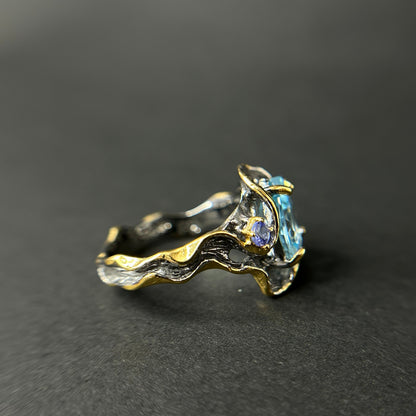 Gold and silver ring with gemstones on a dark gray background