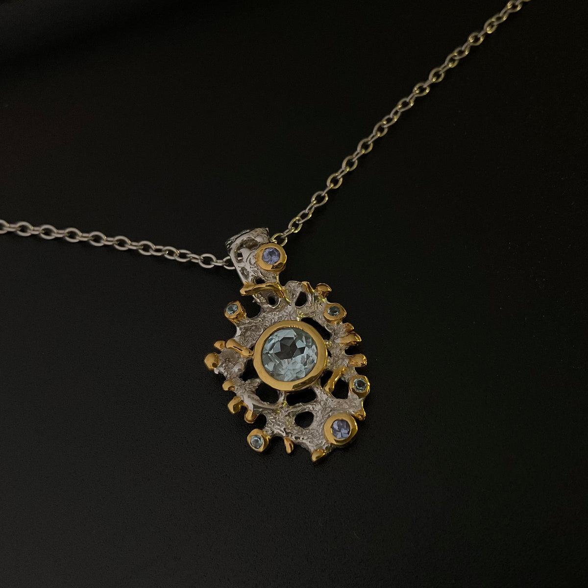 Gold and silver pendant necklace with Topaz gemstones on a black background