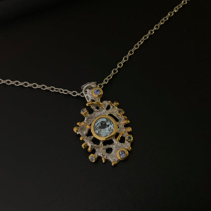 Gold and silver pendant necklace with Topaz gemstones on a black background