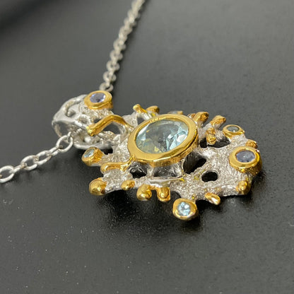 Gold and silver pendant with central Swiss Topaz gemstone on a dark background