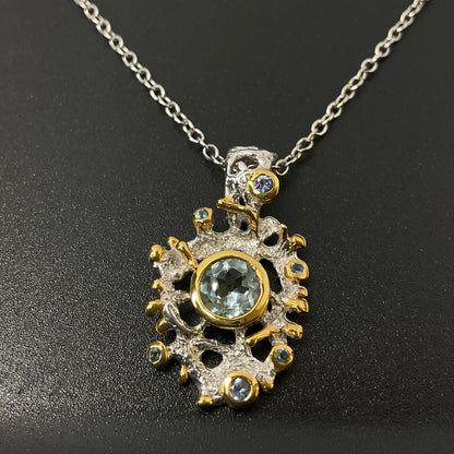 Gold and silver pendant with central Swiss Topaz gemstone on a dark background