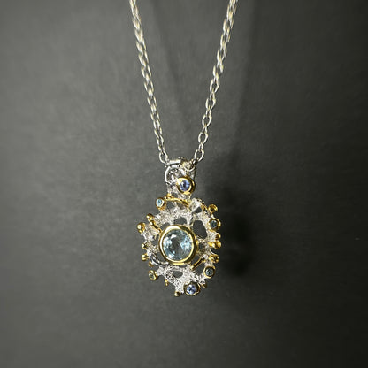 Gold and silver pendant with central Swiss Topaz gemstone on a dark background