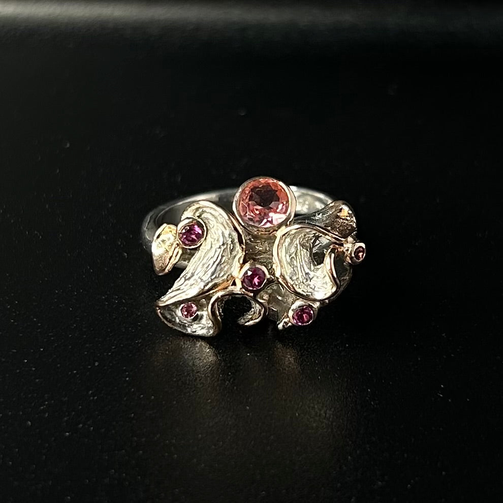 Silver ring with pink tourmaline gemstones on a black background