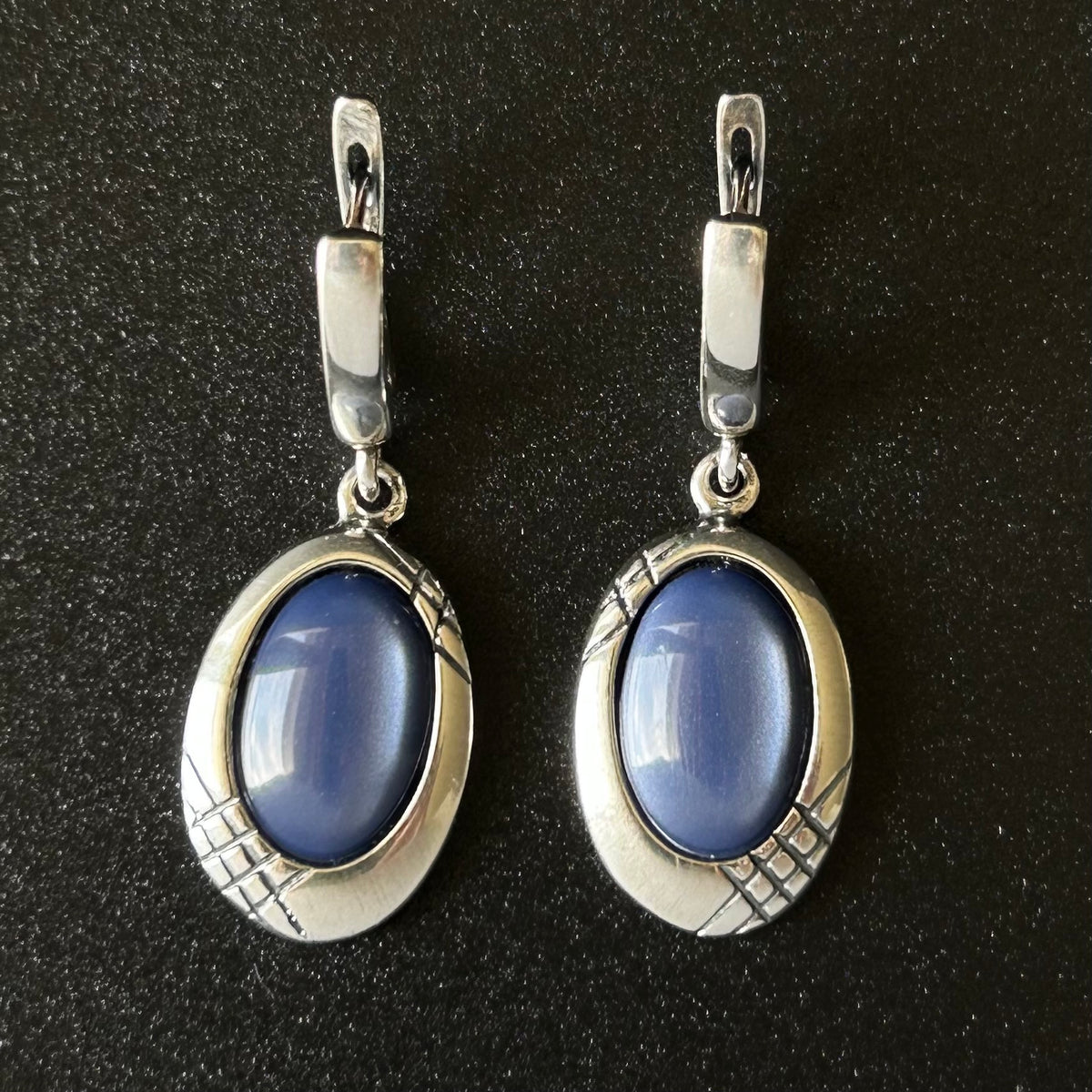 Pair of silver earrings with blue stones on a black background