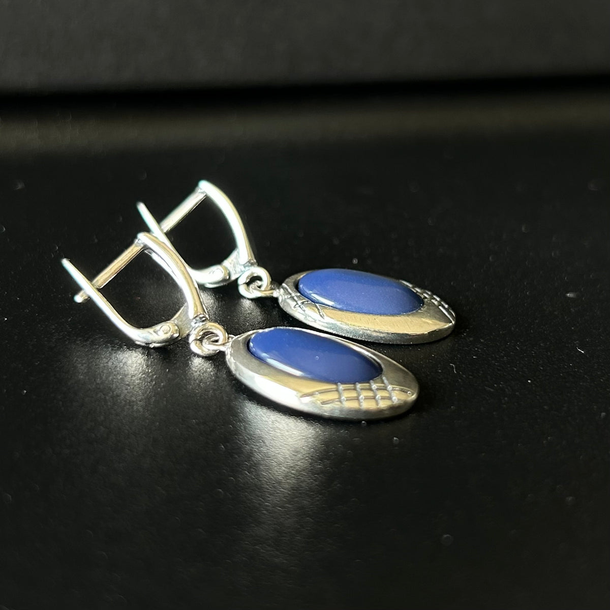 Silver earrings with blue stones on a black background