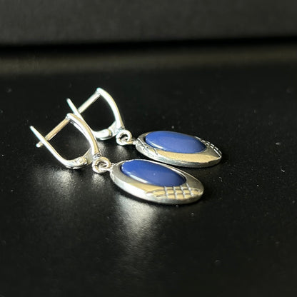 Silver earrings with blue stones on a black background