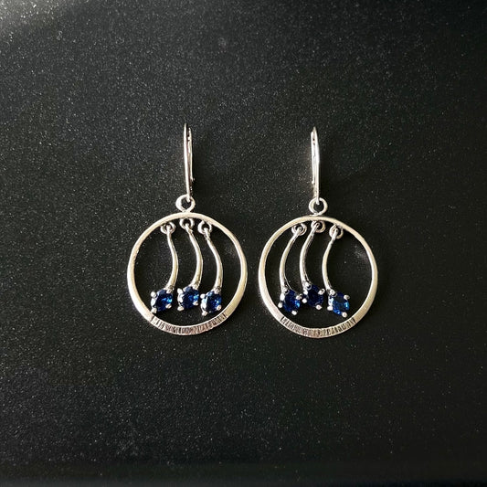 Silver earrings with blue stones on a black background