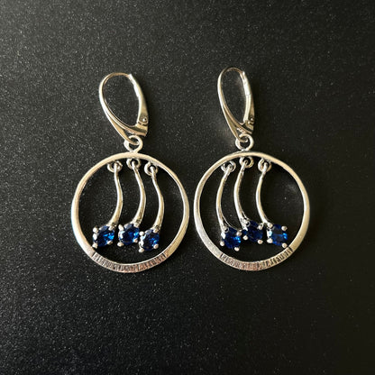 Pair of silver earrings with blue stones on a black background