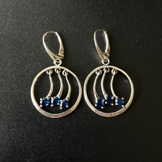Pair of silver earrings with blue stones on a black background
