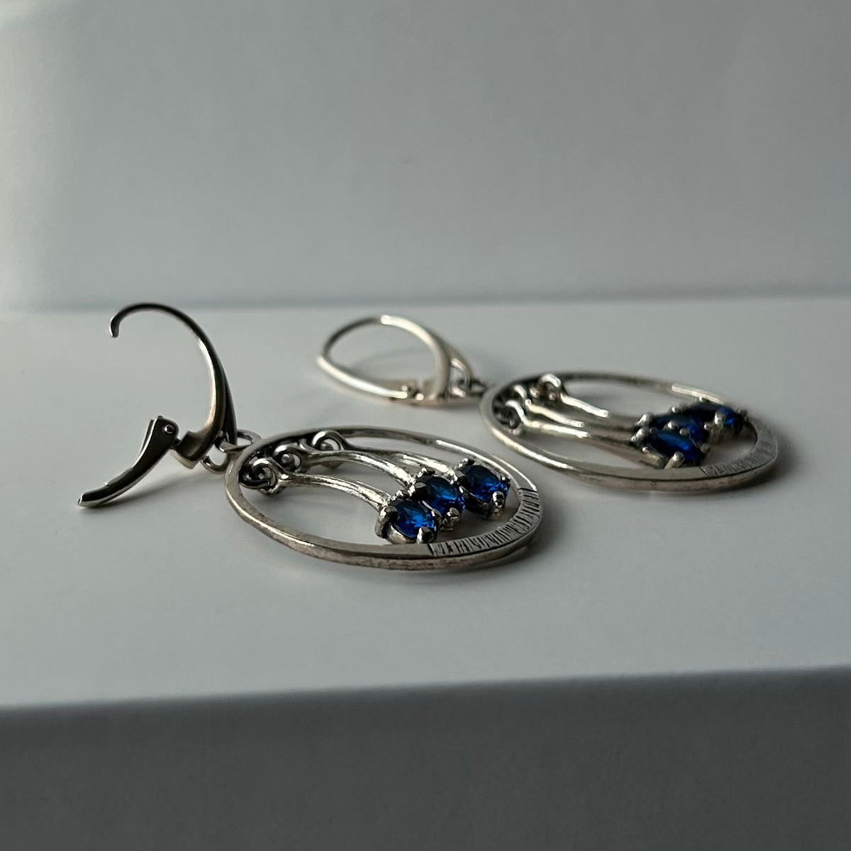 Pair of silver earrings with blue stones on a white background