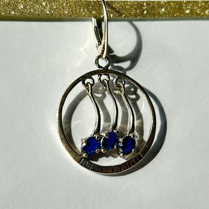 Pair of silver earrings with blue stones on a white background