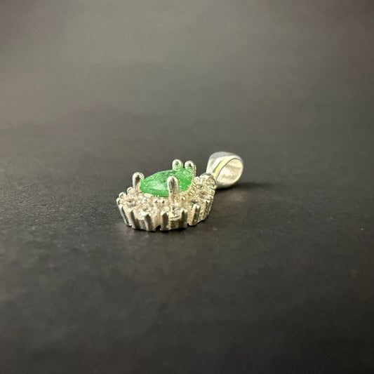 A silver pendant featuring a central green teardrop-shaped gemstone surrounded by a halo of small clear stones