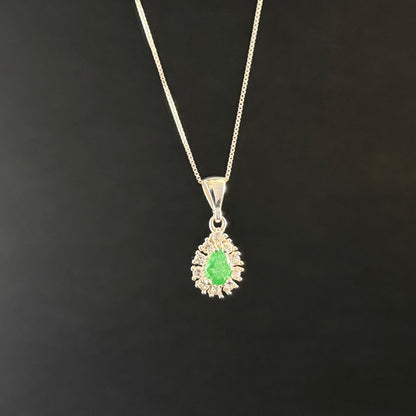 A silver pendant necklace featuring a central green teardrop-shaped gemstone surrounded by a halo of small clear stones