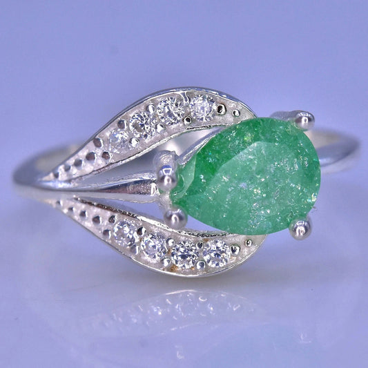 A silver ring featuring a large, faceted green gemstone in an oval shape, surrounded by small clear stones set in a leaf-like design